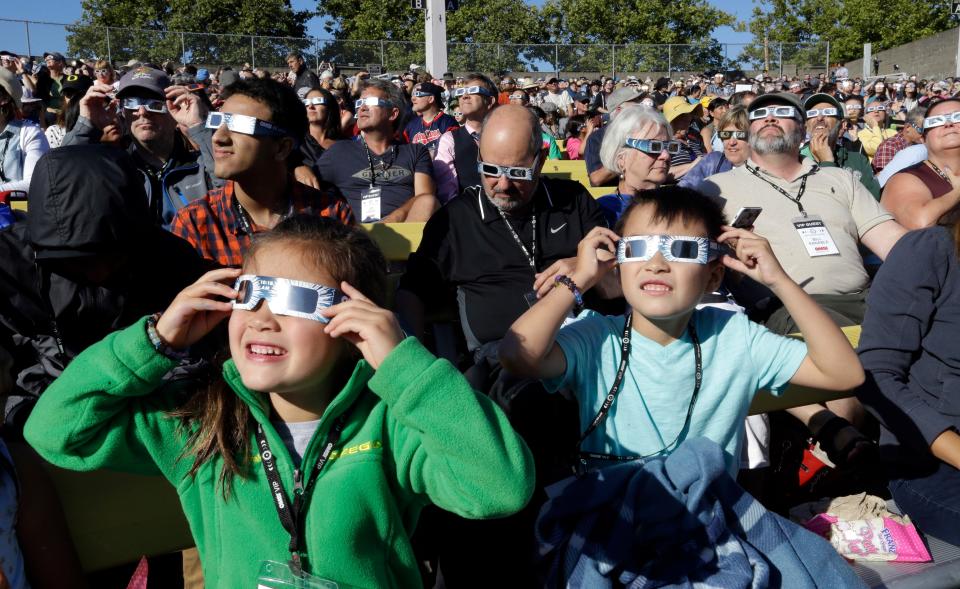 A crowd wears protective glasses as they watch the beginning of the solar eclipse from Salem, Ore. on Aug. 21, 2017. 