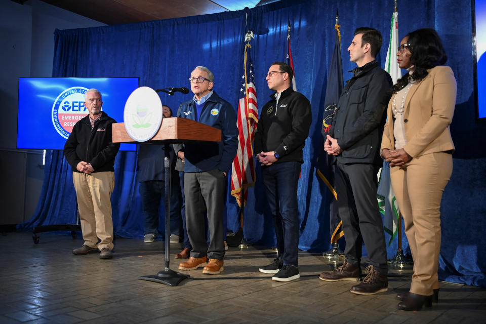 Ohio Gov. Mike DeWine stands at a podium, flanked by other local, state and national leaders, at a news conference 