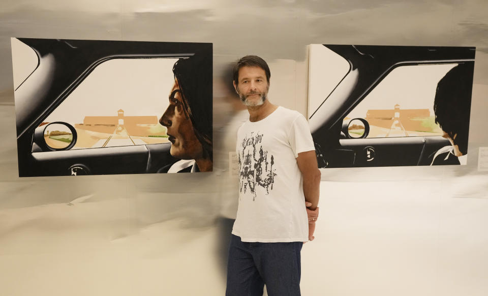 Polish artist Wilhelm Sasnal poses in front of one of his art works on display in a new exhibition at the POLIN Museum of the History of Polish Jews, in Warsaw, Poland, on Tuesday June 15, 2021. "Wilhem Sasnal: Such a Landscape" opened Thursday. The dozens of paintings and drawings on display confront the Holocaust in the nation's physical and mental landscape and the difficulty in Poland in addressing an unsettled past.(AP Photo/Czarek Sokolowski)