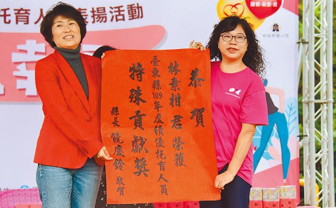 從事保母23年的林素柑（右）獲特殊貢獻獎，由台東縣長饒慶鈴（左）頒發紅榜祝賀。 （莊哲權攝）