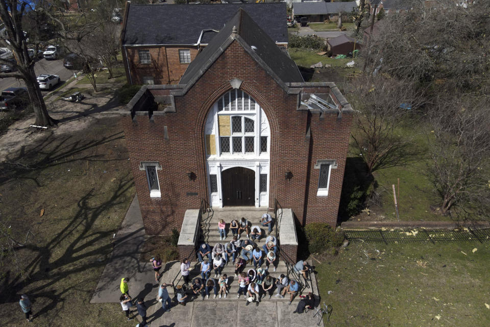 People worship on the steps of the Rolling Fork United Methodist Church, right, as damage is visible to surrounding properties, Sunday, March 26, 2023, in Rolling Fork, Miss. Emergency officials in Mississippi say several people have been killed by tornadoes that tore through the state on Friday night, destroying buildings and knocking out power as severe weather produced hail the size of golf balls moved through several southern states. (AP Photo/Julio Cortez)