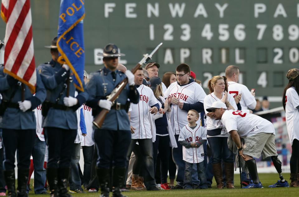 Boston Marathon bombing survivors including Marc Fucarile, lower right, gather on the field at Fenway Park during ceremonies marking the one-year anniversary of the bombing before a baseball game between the Boston Red Sox and the Baltimore Orioles in Boston, Sunday, April 20, 2014. (AP Photo/Michael Dwyer)