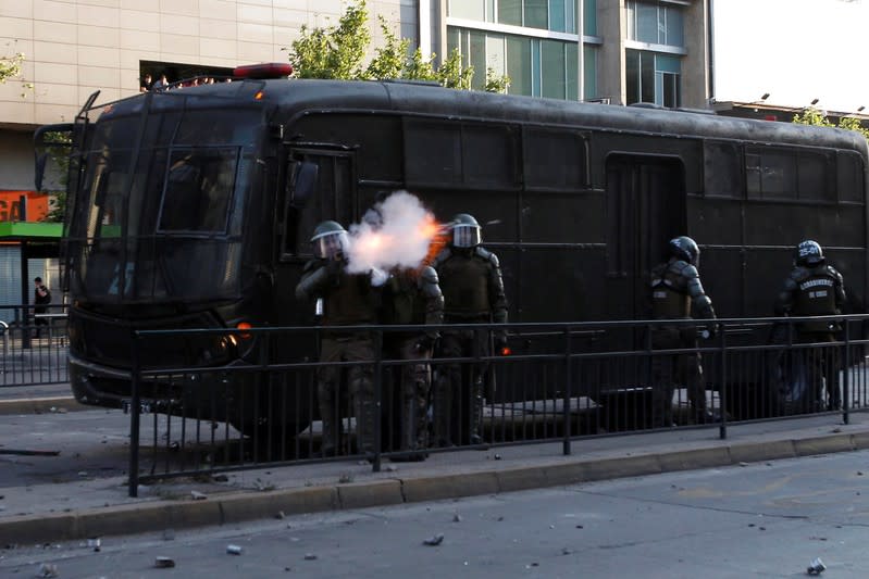 A riot police officer shoot a tear gas canister during a protest against the increase in the subway ticket prices in Santiago