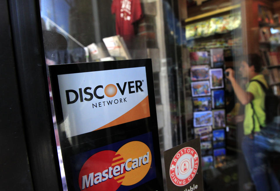 A Discover logo is adhered to a window at the entrance of a shop in Cambridge, Mass., Monday, Sept. 24, 2012. Discover Bank is paying $214 million to settle charges that it pressured credit card customers to buy costly add-on services like payment protection and credit monitoring. (AP Photo/Steven Senne)