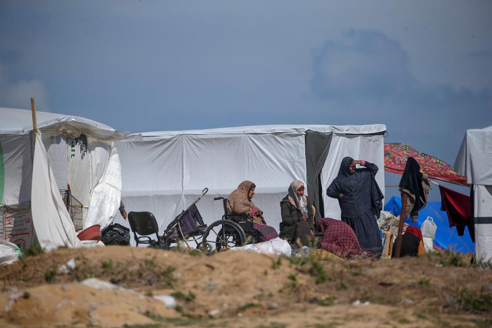 A Palestinian family displaced from Rafah sits outside their shelter in Deir Al Balah, southern Gaza Strip, 14 February 2024 (EPA)