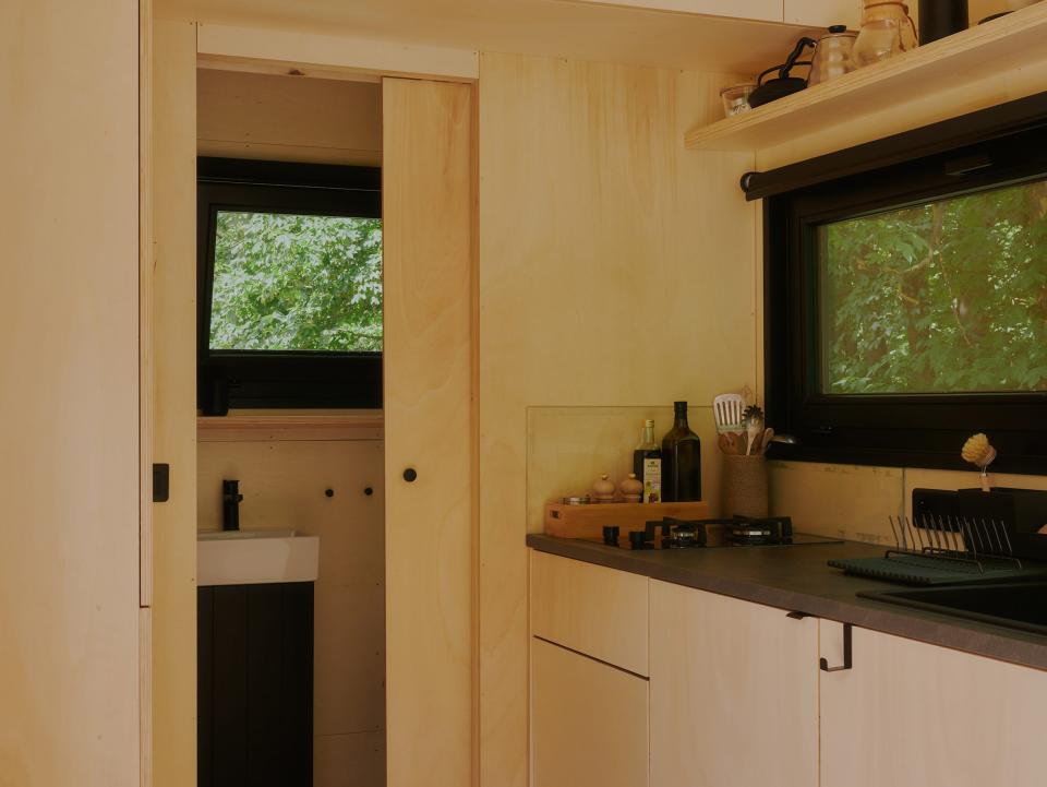 A look inside a Raus cabin with a bathroom, kitchen, windows with views of nature.