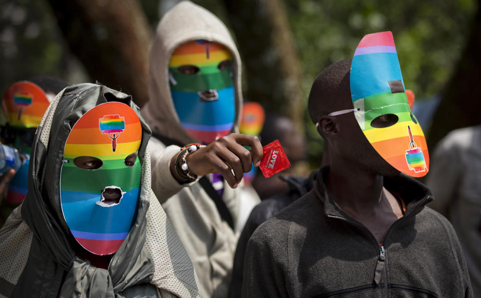 FILE - In this Monday, Feb. 10, 2014 file photo, Kenyan gays and lesbians and others supporting their cause wear masks to preserve their anonymity and one holds out a condom, as they stage a rare protest, against Uganda's increasingly tough stance against homosexuality and in solidarity with their counterparts there, outside the Uganda High Commission in Nairobi, Kenya. Uganda's President Yoweri Museveni is expected to sign Monday, Feb. 24, 2014 a controversial anti-gay bill that allows harsh penalties for homosexual offenses, a bill which rights groups have condemned as draconian in a country where homosexuality is already illegal. (AP Photo/Ben Curtis, File)