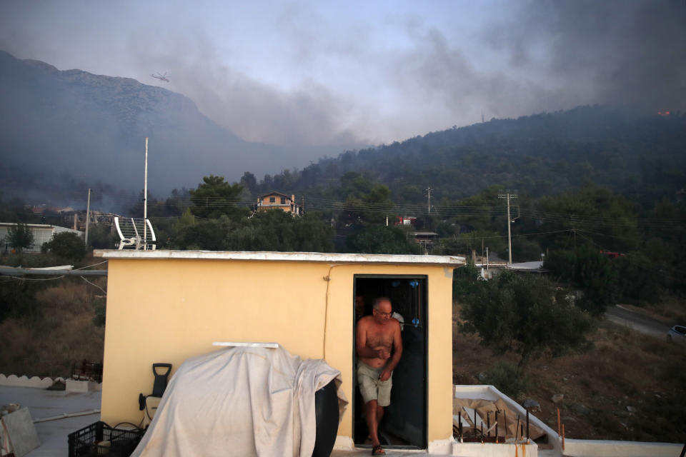 A local resident walks out of the rooftop of his house during a wildfire in Peania, eastern Athens, Monday, Aug. 12, 2019. A big fire broke out in the Athens suburb of Peania east of the city, and authorities ordered the evacuation of nearby houses. (AP Photo/Thanassis Stavrakis)