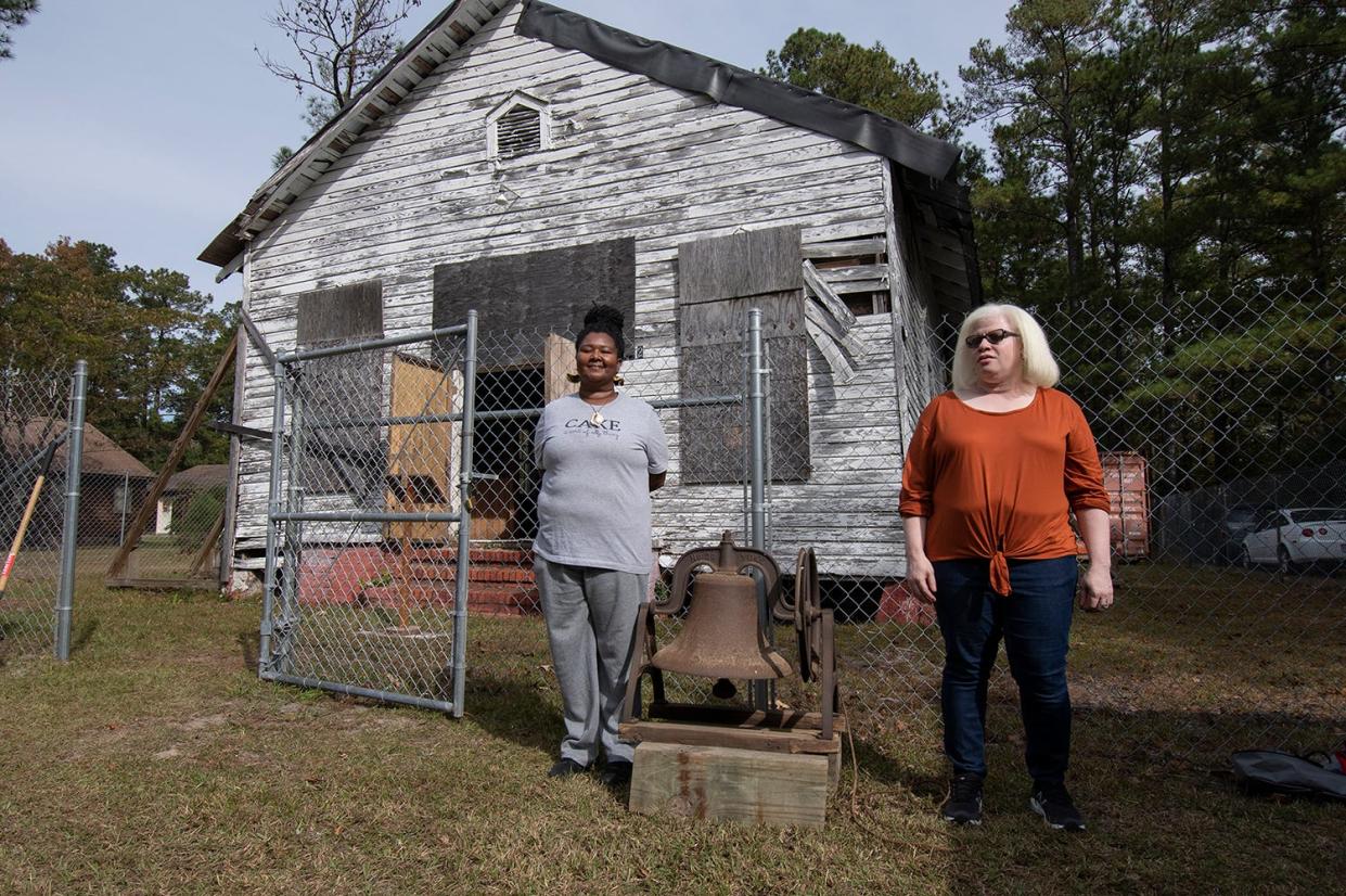 Jacki Davis and Kariba David, representing all past members of the congregation and their descendants, stand with the Reaves Chapel bell.