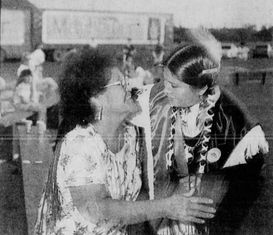 Clissene Lewis (right) greets Ophelia Kill during a powwow in the Fort McDowell Indian Community. The Mayflower trucks in the background hold gaming equipment seized by the FBI. (Published May 14, 1992)