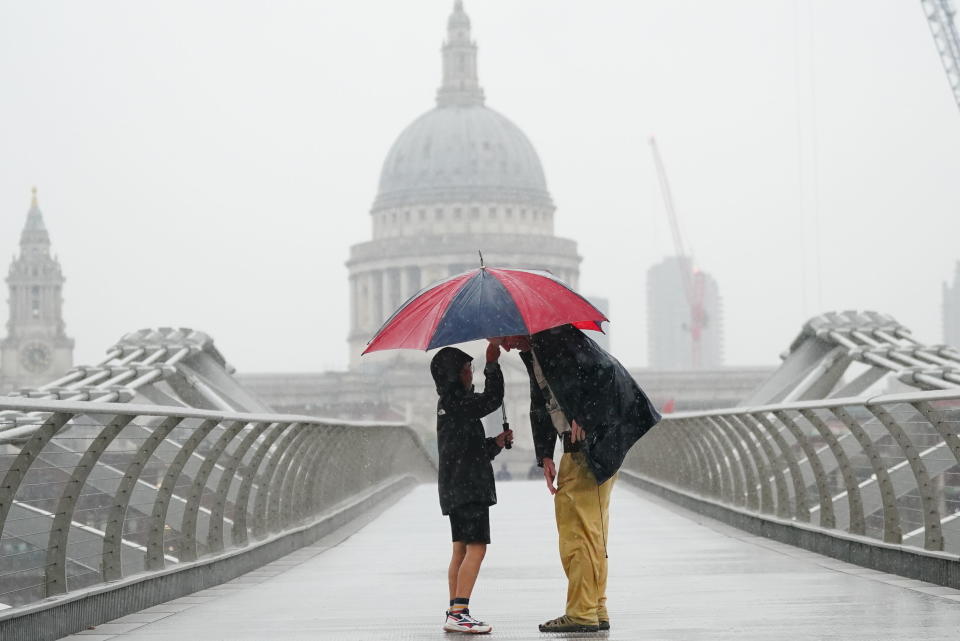 People shelter with an umbrella in the rain in London, Wednesday Aug. 17, 2022.. After weeks of sweltering weather, which has caused drought and left land parched, the Met Office's yellow thunderstorm warning forecasts torrential rain and thunderstorms that could hit parts England and Wales. (Victoria Jones/PA via AP)