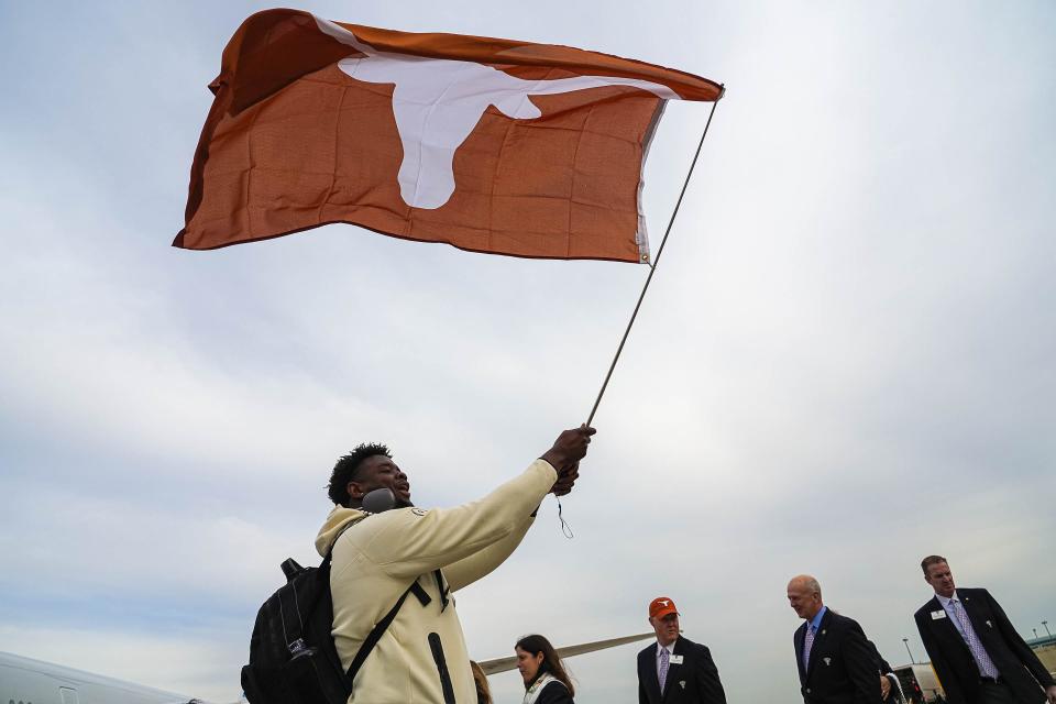 Texas offensive lineman Christian Jones waves a Longhorns flag as he exits the team plane in New Orleans ahead of the Sugar Bowl. The veteran lineman is one of 11 Longhorns who were invited to this year's NFL scouting combine.