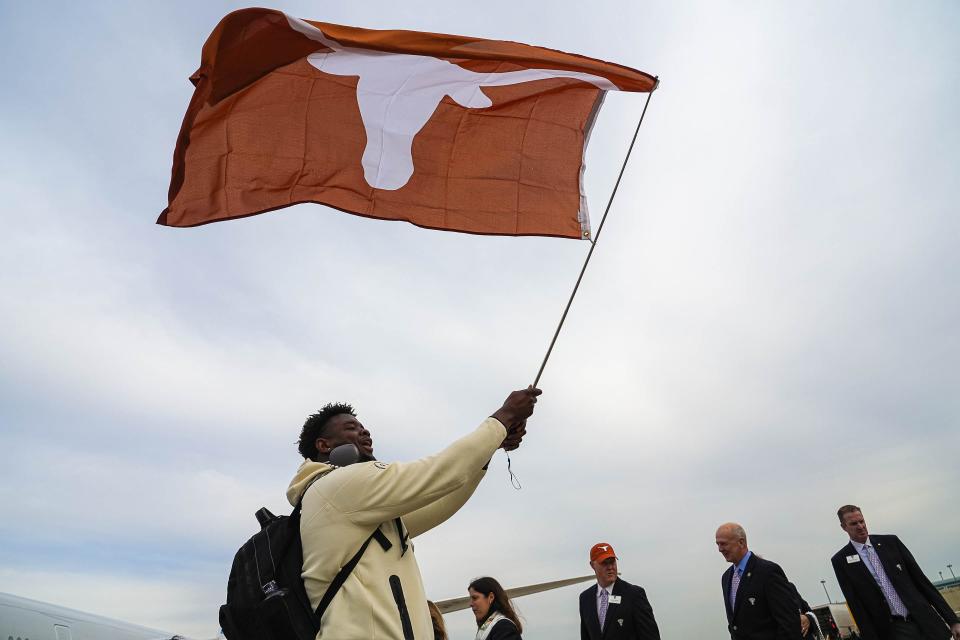 Texas right tackle Christian Jones waves a Longhorns flag as he exits the team plane at Louis Armstrong International Airport in New Orleans on Wednesday. The Longhorns have reached their first College Football Playoff.