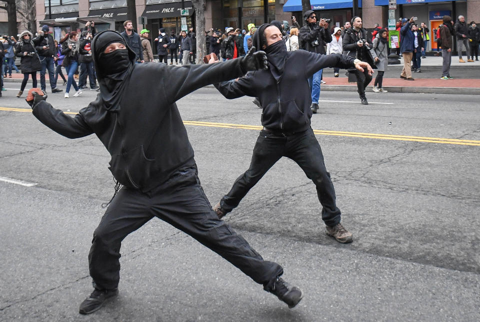Protesters throw rocks at police during a protest near the inauguration site. (Photo: Bryan Woolston / Reuters)