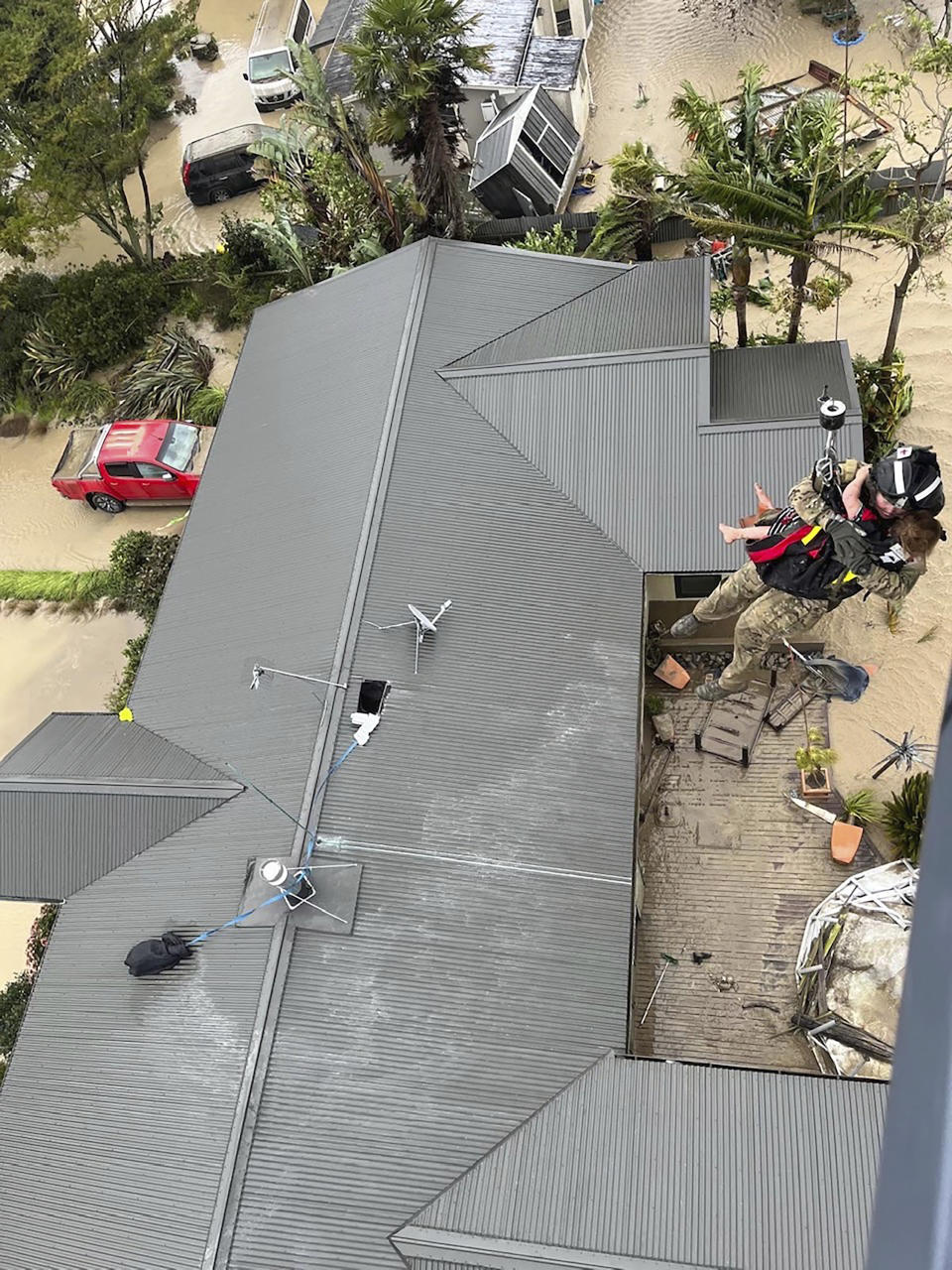 In this image released by the New Zealand Defense Force on Wednesday, Feb. 15, 2023, a child is winched from a rooftop of a home to safety by helicopter in the Esk Valley, near Napier, New Zealand. The New Zealand government declared a national state of emergency Tuesday after Cyclone Gabrielle battered the country's north in what officials described as the nation's most severe weather event in years. (New Zealand Defense Force via AP)