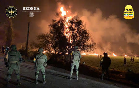 Military personnel watch as flames light up the night’s sky. Source: Reuters