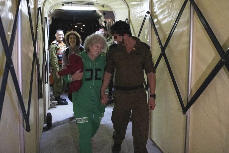 Ruth Munder, a released Israeli hostage, walks with an Israeli soldier shortly after her arrival in Israel on Friday, Nov. 24, 2023. A four-day cease-fire in the Israel-Hamas war began in Gaza on Friday with an exchange of hostages and prisoners. (IDF via AP)