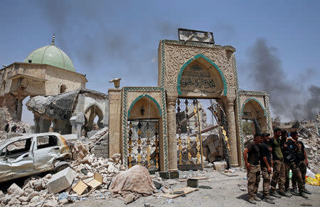 Members of Iraqi forces pose in front of the ruined Grand al-Nuri mosque in the Old City in Mosul, Iraq July 2, 2017. REUTERS/Erik De Castro