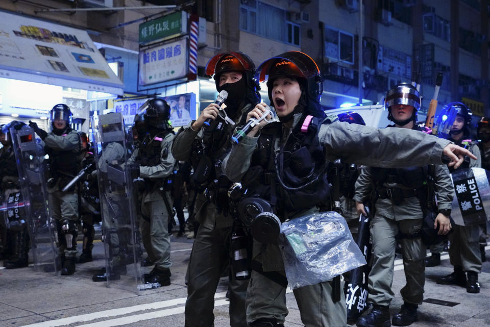 Police officers using speakers to warn protesters on the street of Yuen Long, Hong Kong, Monday, Oct. 21, 2019. A evening sit-in at a suburban train station on the three-month anniversary of a violent attack there on protesters by men with suspected organized crime ties. (AP Photo/Vincent Yu)