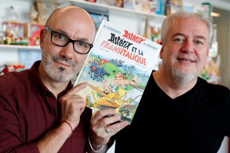 Author Jean-Yves Ferri (L) and illustrator Didier Conrad (R) pose with a copy of their new comic album "Asterix et la Transitalique" (Asterix and the Chariot Race) after an interview in Vanves near Paris, France, October 17, 2017, the latest in the series created by illustrator Albert Uderzo and writer Rene Goscinny in 1959. Picture taken October 17, 2017. REUTERS/Philippe Wojazer