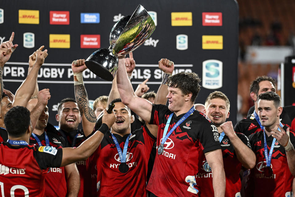 Crusaders captain Scott Barrett holds the trophy aloft as he celebrates with teammates after defeating the chiefs in the Super Rugby Pacific final in Hamilton, New Zealand, Saturday, June 24, 2023. (Andrew Cornaga/Photosport via AP)