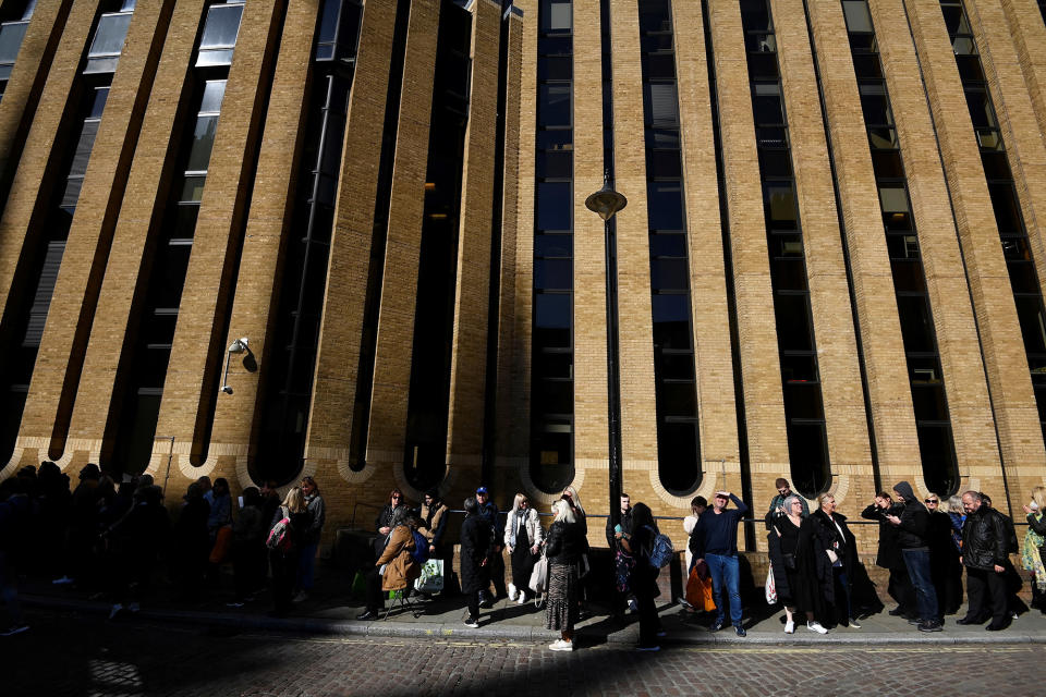 People stand outside a tall, brick building