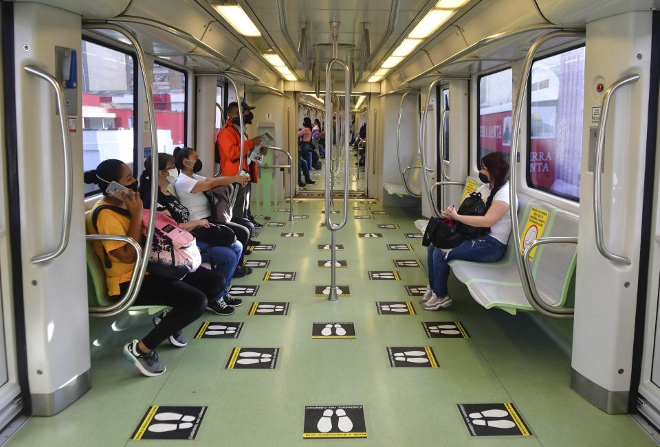 In this June 8, 2020 photo, commuters travel on a train marked with social distancing graphic cues, amid the new coronavirus pandemic, in Medellin, Colombia. The metropolis recently went five weeks without a single COVID-19 death. (AP Photo/Luis Benavides)