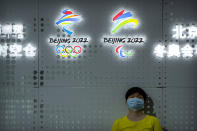 FILE - A visitor rests near the logos of the Beijing 2022 Winter Olympics and Paralympics at the China Beijing International High-Tech Expo in Beijing on Sept. 25, 2021. The Beijing Winter Olympics open in just under two months and are now the target to a diplomatic boycott by the United States with others likely to follow. (AP Photo/Mark Schiefelbein, File)