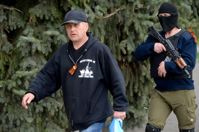 Leader of the separatist rebels in the eastern Ukrainian city of Slavyansk, Vyacheslav Ponomaryov (L), escorted by an armed man, in Slavyansk on April 20, 2014