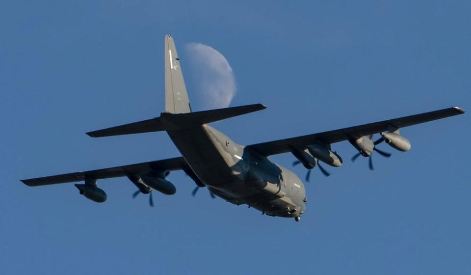 A photo of an MC-130J Commando II flying in the sky with the moon in the background.