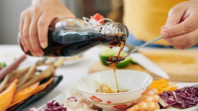 Woman pouring soy sauce into bowl