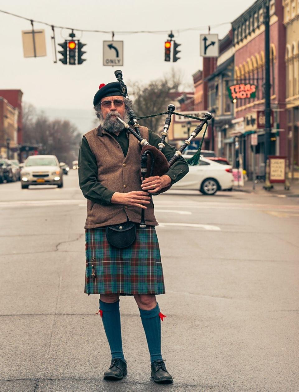 Stephen Walker plays the bagpipe in downtown Wellsville. Walker has plenty of photos that were taken locally, but he is on a quest to find a photograph of him playing the bagpipe as a street performer in Europe during the mid 1970s.