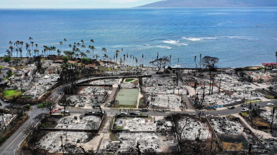 PHOTO: In an aerial view, a recovery vehicle drives past burned structures and cars two months after a devastating wildfire, Oct. 9, 2023, in Lahaina, Hawaii.  (Mario Tama/Getty Images)