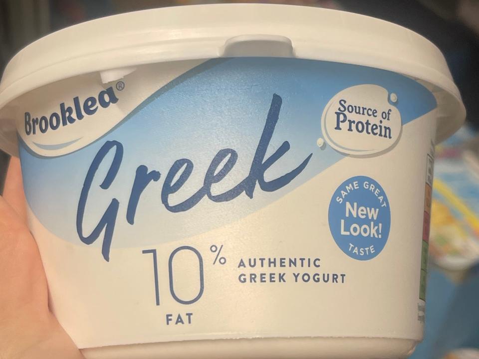 hand holding up a tub of greek yogurt at aldi