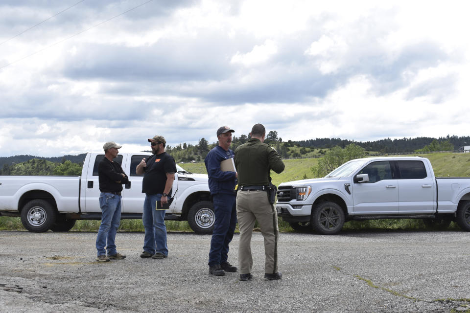 Local authorities are on the scene as heavy equipment is staged to begin removing the wreckage after a bridge collapse near Columbus, Mont., Saturday, June 24, 2023. The bridge collapsed overnight, causing a train that was traveling over it to plunge into the water below. Authorities on Sunday were testing the water quality along a stretch of the Yellowstone River where mangled cars carrying hazardous materials remained after crashing into the waterway. (AP Photo/Matthew Brown)