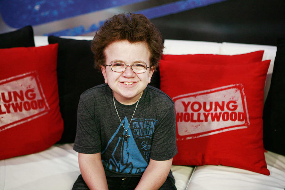 Keenan smiling with Young Hollywood pillows behind him