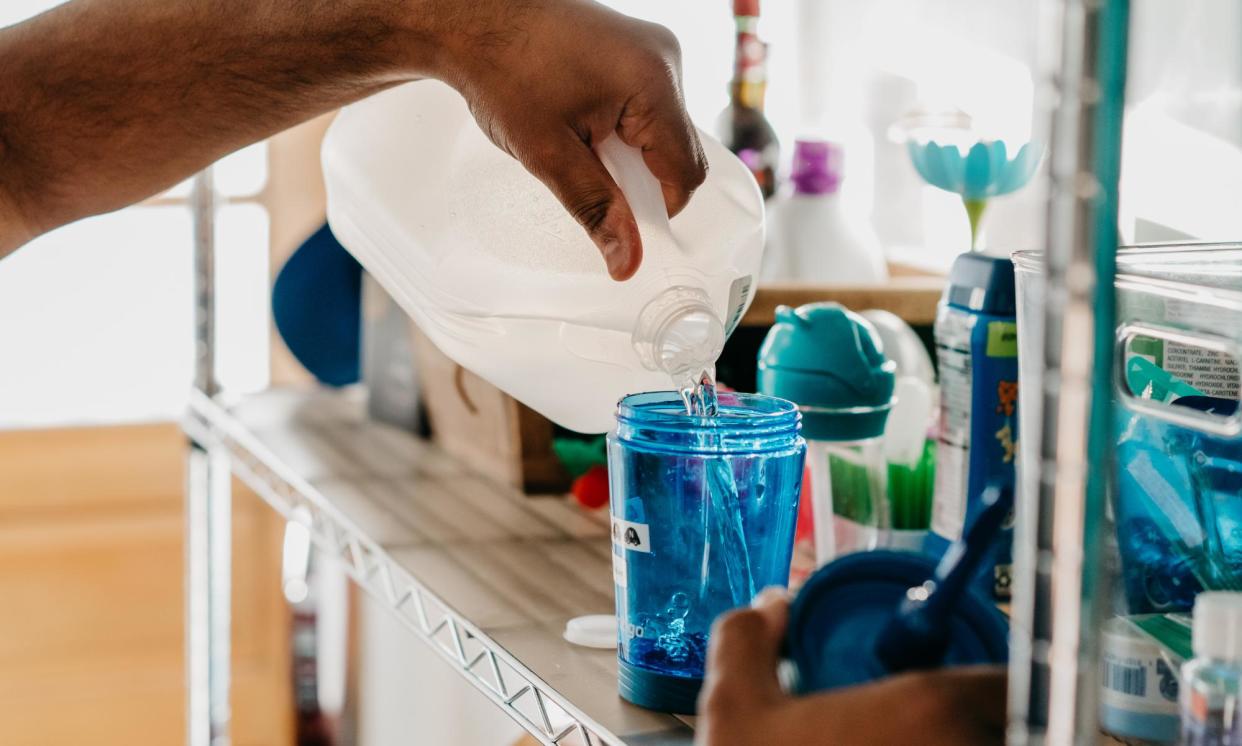 <span>An man pours water into a cup for his son at his home in Chicago, Illinois, on 29 July 2022.</span><span>Photograph: Jamie Kelter Davis/The Guardian</span>