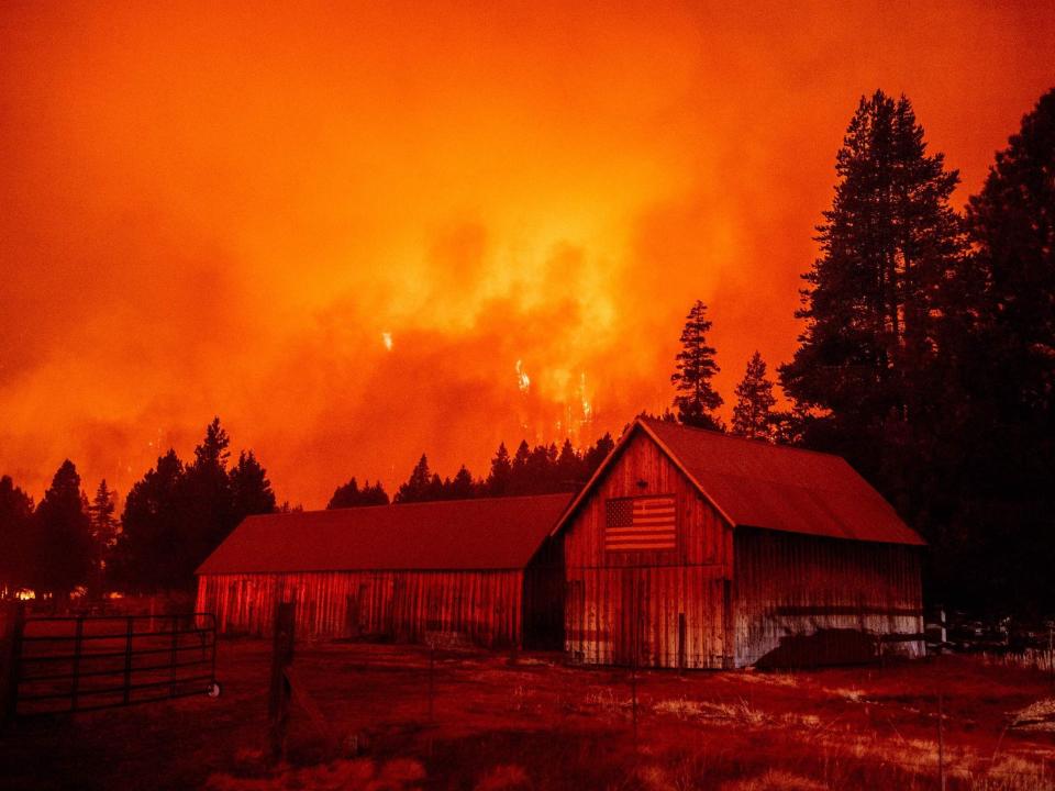 Flames from the Caldor fire stretch into the sky behind a barn near Lake Tahoe