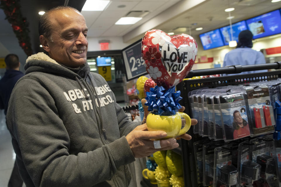 In this Tuesday, Dec. 3, 2019, photo, Mohammed Hafar buys a gift for his daughter Jana Hafar while waiting for her flight at JFK Airport in New York. Jana had been forced by President Donald Trump's travel ban to stay behind in Syria for months while her father, his wife and son Karim started rebuilding their lives in Bloomfield, N.J., with no clear idea of when the family would be together again. Mohammed was part of a federal lawsuit filed in August of this year over the travel ban waiver process. (AP Photo/Mary Altaffer)