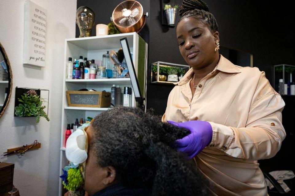 Hadassa Félix, estilista capilar y emprendedora haitianoamericana, trabaja en el cabello enmarañado de una clienta el 24 de mayo de 2023, dentro de su salón llamado Love 518 en La Pequeña Habana. Esta clienta viajó desde Nueva York.