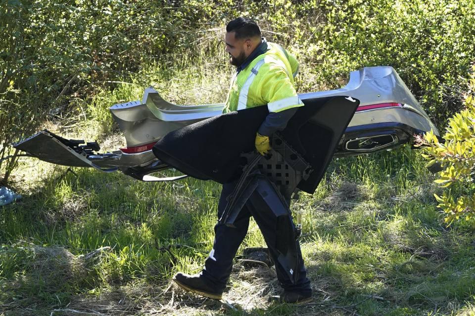 A worker moves debris after a rollover accident involving golfer Tiger Woods Tuesday, Feb. 23, 2021, in Rancho Palos Verdes, Calif., a suburb of Los Angeles. Woods suffered leg injuries in the one-car accident and was undergoing surgery, authorities and his manager said. (AP Photo/Marcio Jose Sanchez)