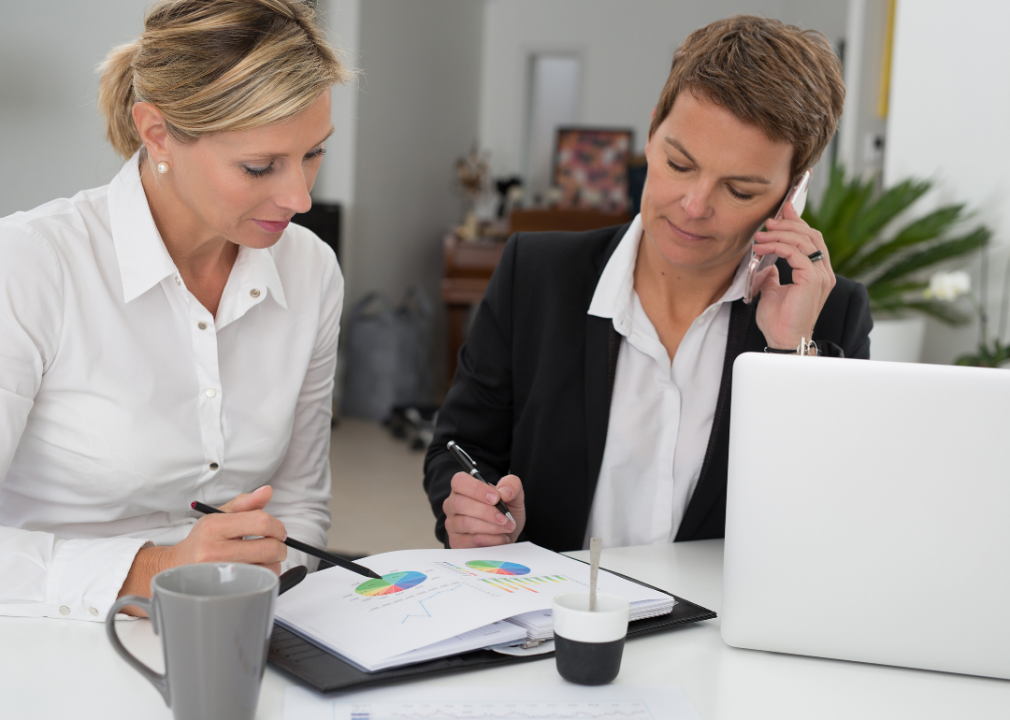 Two people work together at a table, looking at a sheet of paper with pie charts.