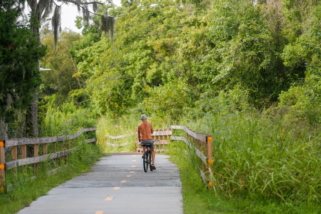 A bicycle rider takes the Truman Linear Park Trail toward Lake Mayer.