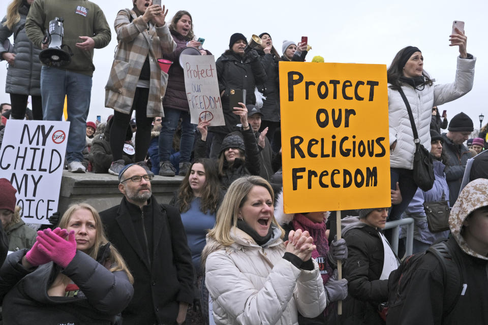 People hold signs during a protest at the state house in Trenton, N.J., Monday, Jan. 13, 2020. New Jersey lawmakers are set to vote Monday on legislation to eliminate most religious exemptions for vaccines for schoolchildren, as opponents crowd the statehouse grounds with flags and banners. (AP Photo/Seth Wenig)