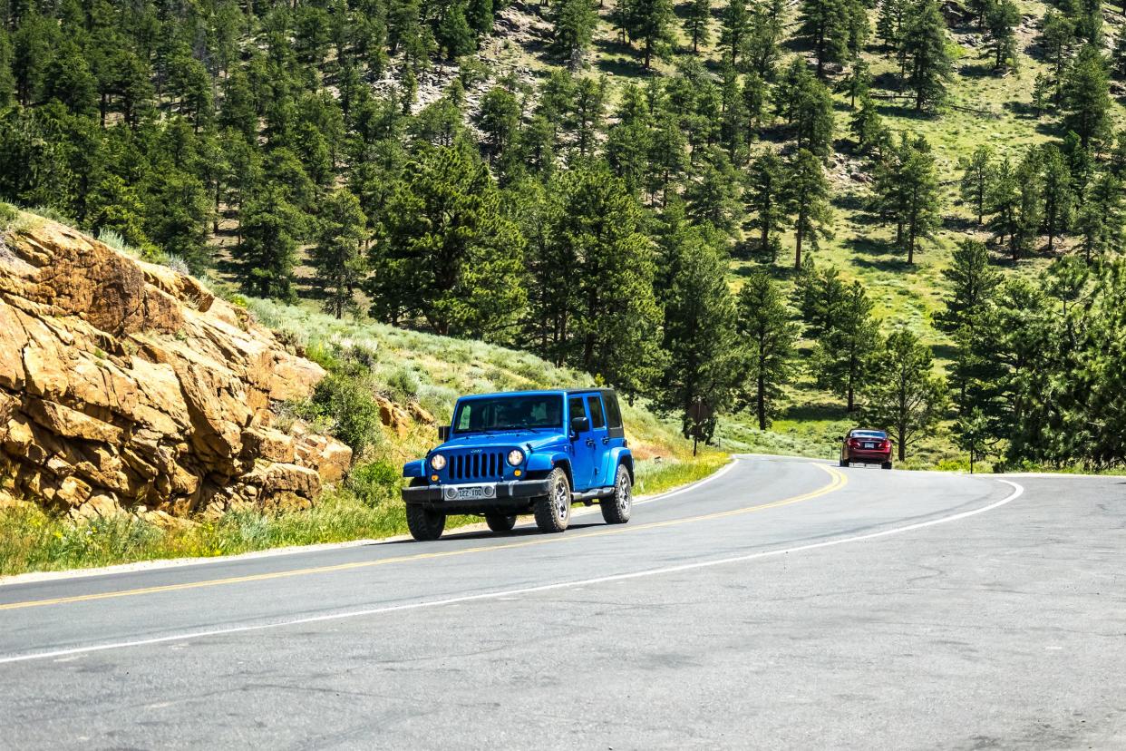 Blue Jeep Wrangler on a winding mountain road in the Rocky Mountain National Park.