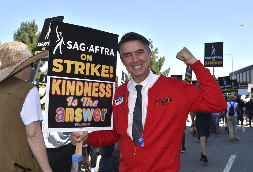 El actor Walt Keller vestido como Mister Rogers con un letrero fuera de una manifestación en Universal Studios el 4 de agosto de 2023, en Universal City, California. (Foto Richard Shotwell/Invision/AP)