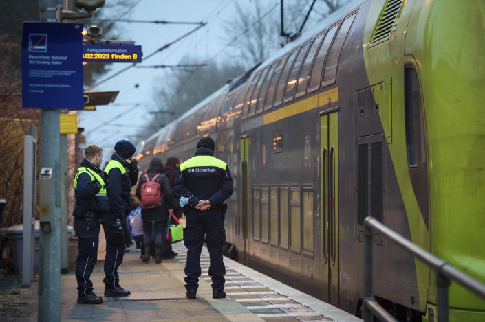 Deutsche Bahn security guards stand on the platform at Brokstedt station at dawn in Brokstedt, Germany, Thursday, Jan.26, 2023. Two people were killed and seven injured in a knife attack on a regional train from Kiel to Hamburg on Jan. 25, 2023. (Gregor Fischer/dpa via AP)