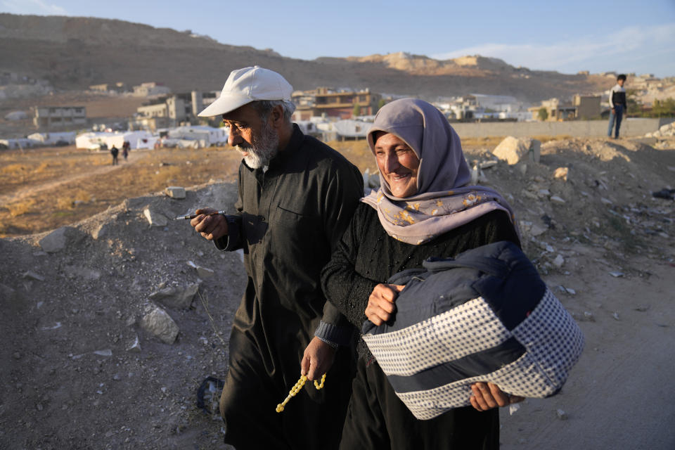 A Syrian refugee woman carries his luggage, as she walks toward to a gathering point where other refugees prepare to back home to Syria, in the eastern Lebanese border town of Arsal, Lebanon, Wednesday, Oct. 26, 2022. Several hundred Syrian refugees boarded a convoy of trucks laden with mattresses, water and fuel tanks, bicycles – and, in one case, a goat – Wednesday morning in the remote Lebanese mountain town of Arsal in preparation to return back across the nearby border.(AP Photo/Hussein Malla)