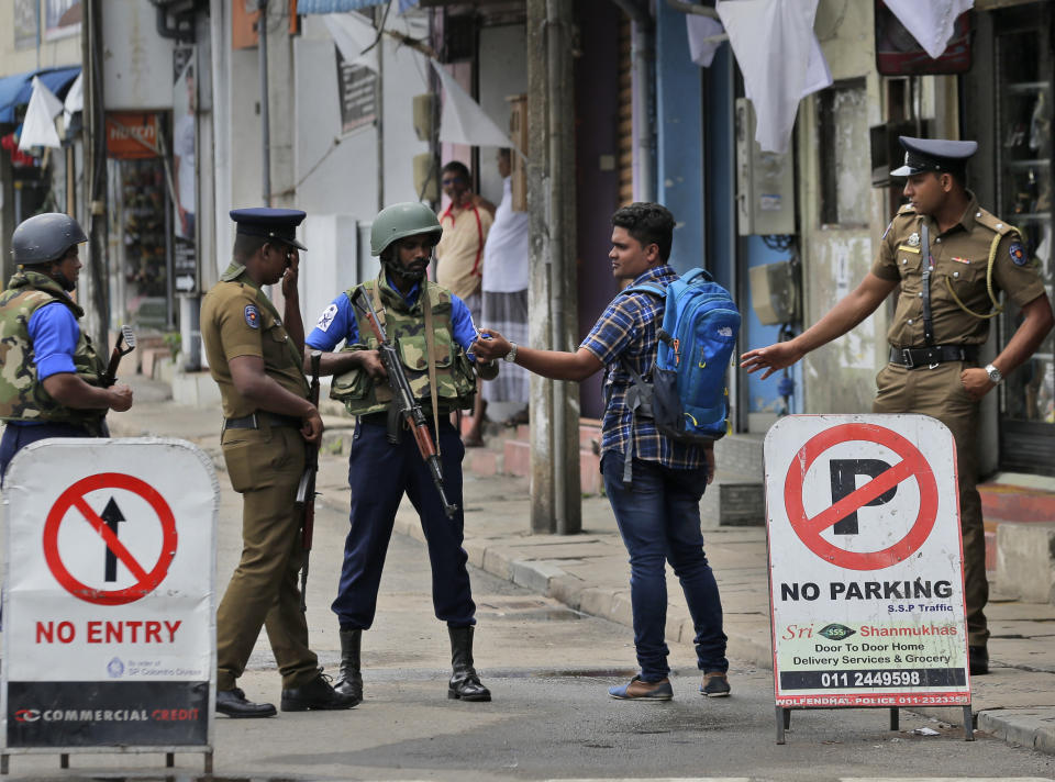 Sri Lankan policemen check the identity card of a person carrying a back-pack, in Colombo, Sri Lanka, Monday, April 29, 2019. The Catholic Church in Sri Lanka says the government should crack down on Islamic extremists with more vigor "as if on war footing" in the aftermath of the Easter bombings. (AP Photo/Eranga Jayawardena)