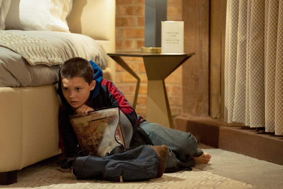 a kid crouches behind a bed holding a comic